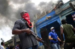 A private security guard stands outside a  burning store in downtown Port-au-Prince